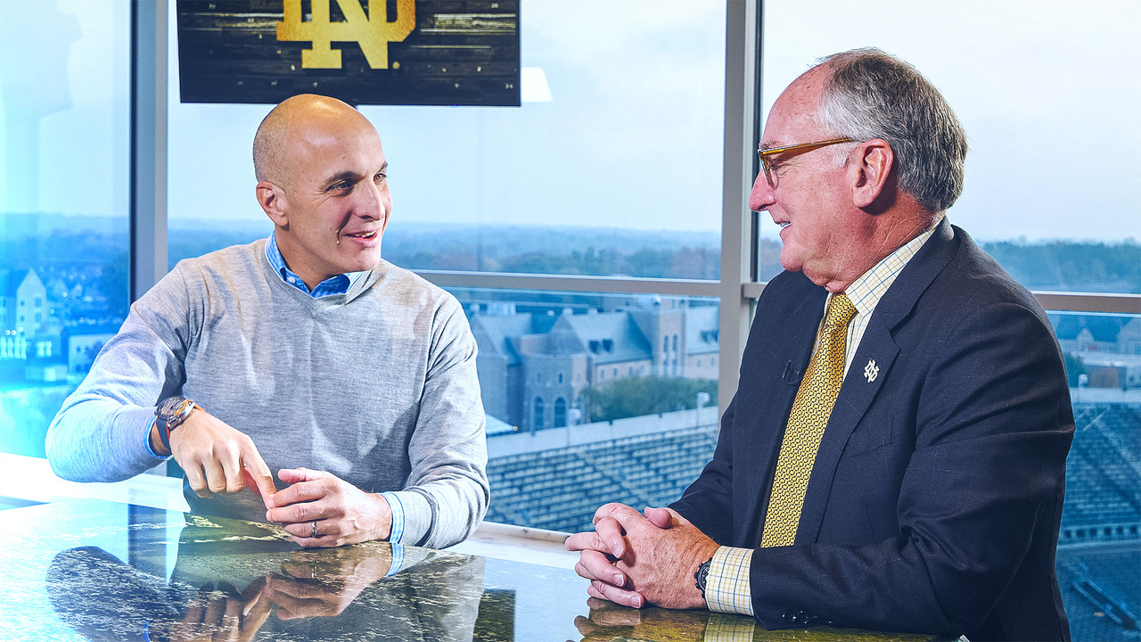 Pete Bevacqua speaks with Jack Swarbrick at a table overlooking Notre Dame Stadium.